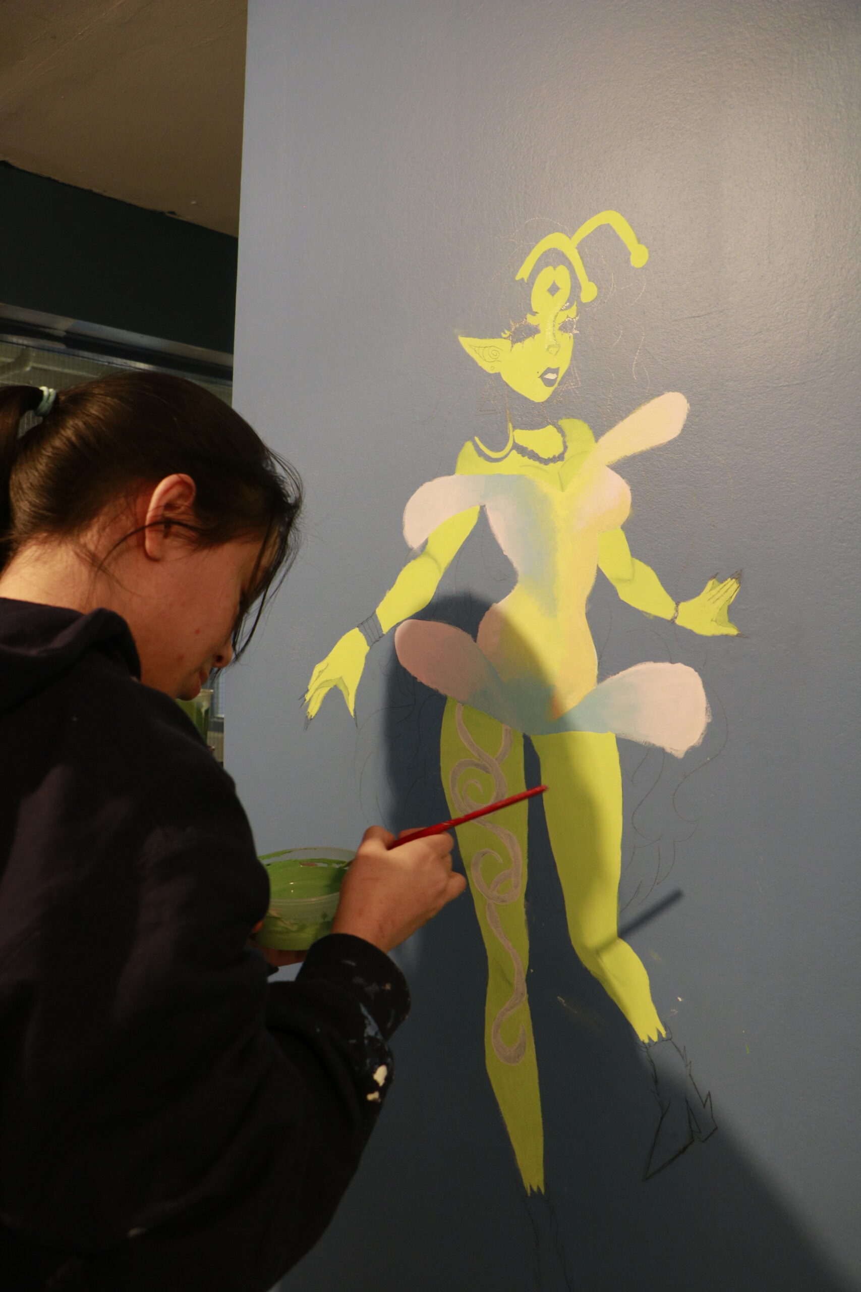 Student painting a figure on a wall